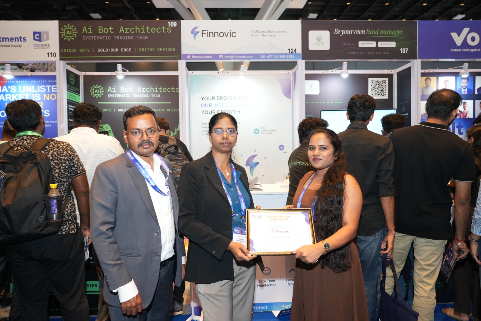Finnovic team members holding the Money Expo India 2026 exhibitor participation certificate at the stand